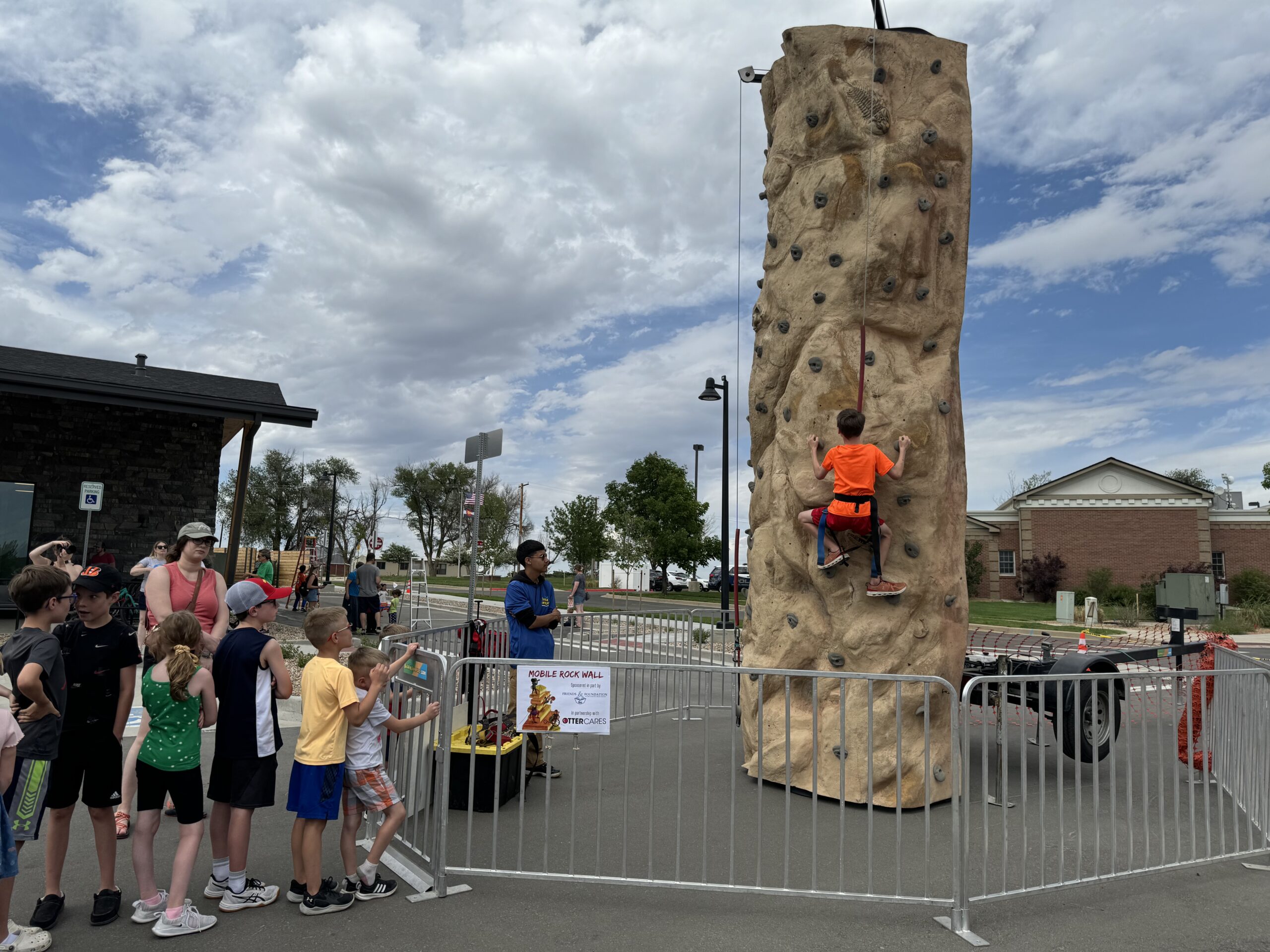 A child climbs a portable rock wall at an outdoor community event.